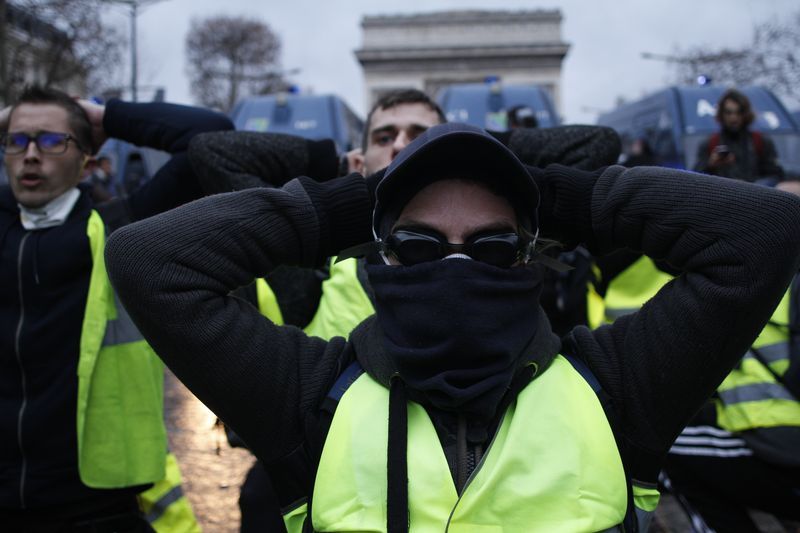 Manifestants qui miment les élèves de Mantes-la-Jolie arrêtés par la police plusieurs jours auparavant, Champs Élysées, une semaine après le saccage de l’Arc de Triomphe lors d’une précédente manifestation de Gilets jaunes , 08 12 2018, Ph. Moctar KANE.